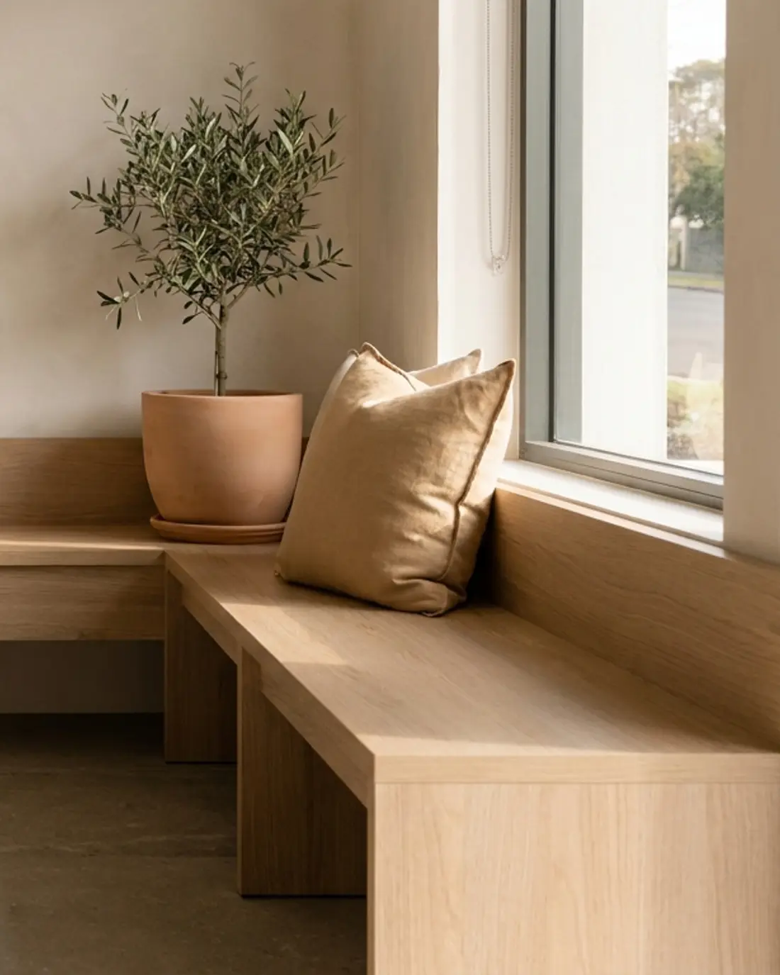 A quiet, sunlit corner of a clinic waiting area with a wooden bench and a plant.